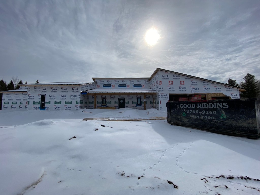 Photo of exterior of house under construction with snow on roof.